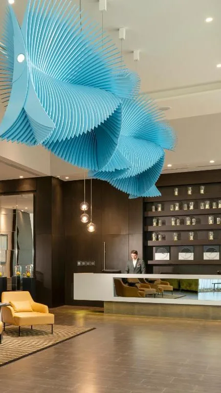 Hall d’accueil d’un hôtel partenaire à Istanbul : sculpture suspendue bleue, comptoir de réception et fauteuils jaunes