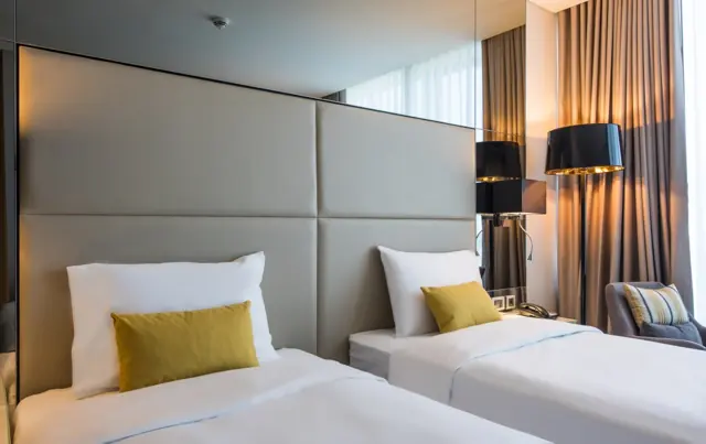 Chambre avec deux lits simples et tête de lit capitonnée