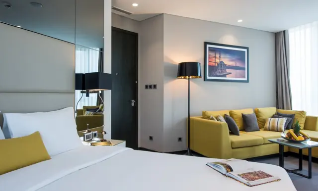 Chambre avec lit double et coin salon avec canapé jaune