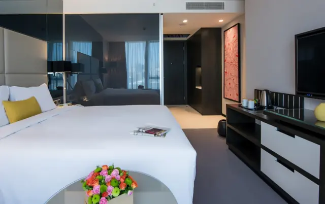 Chambre avec lit double, bouquet de fleurs et meuble télévision