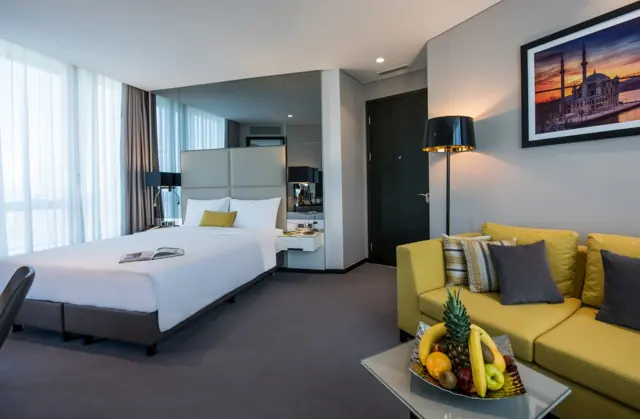Chambre spacieuse avec lit double, canapé et corbeille de fruits