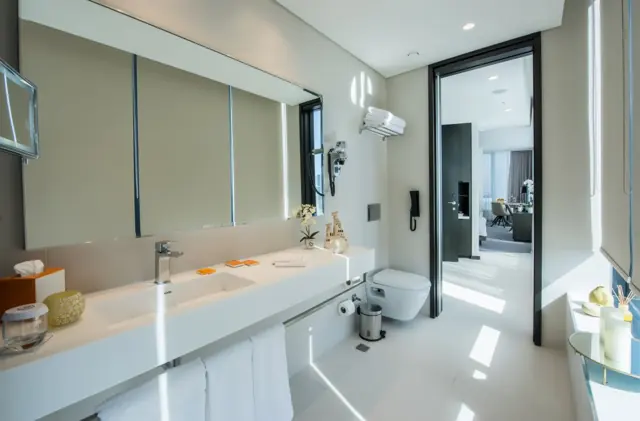 Salle de bains avec vasque et miroir, ouverte sur la chambre