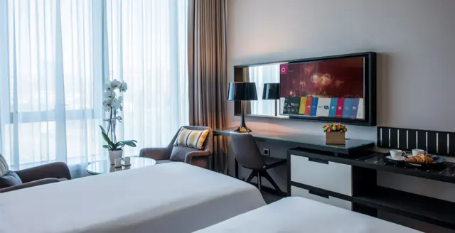 Chambre avec lits simples, bureau et télévision