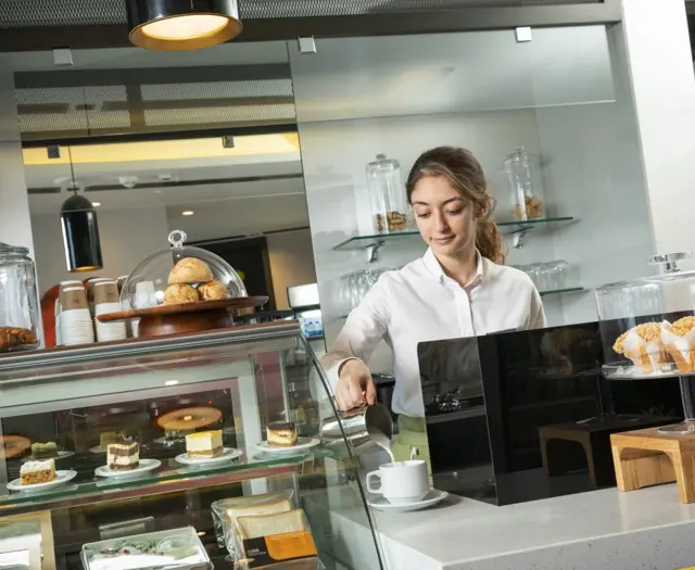 Serveuse derrière le comptoir de pâtisseries