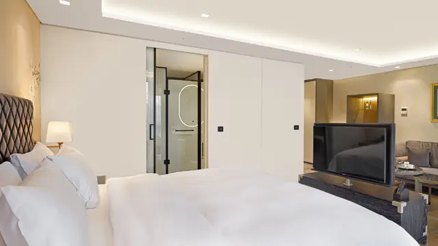 Chambre avec grand lit et télévision, salle de bains en arrière-plan