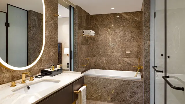 Salle de bains en marbre avec baignoire et miroir lumineux