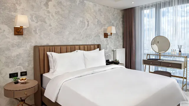 Chambre avec grand lit, coiffeuse et grandes fenêtres